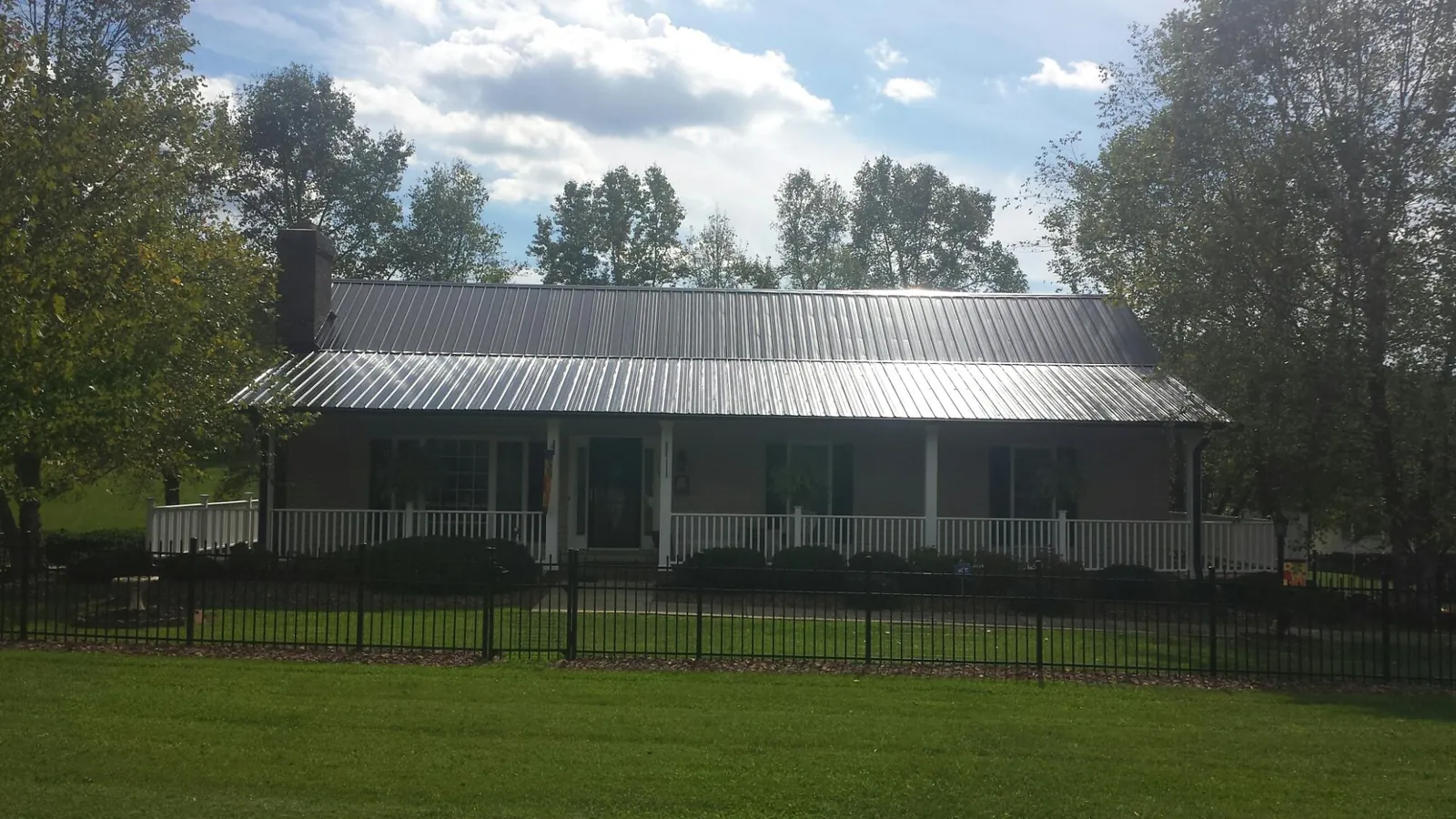 Gray metal roof on a brick ranch with a full width front porch — Gutter Guard Installation work by our crew in Foster